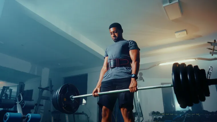 An active adult lifting a barbell in a gym